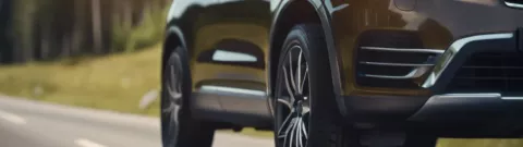 A realistic close shot of a modern SUV's tyre being driven on a road in Norway on a sunny summer day
